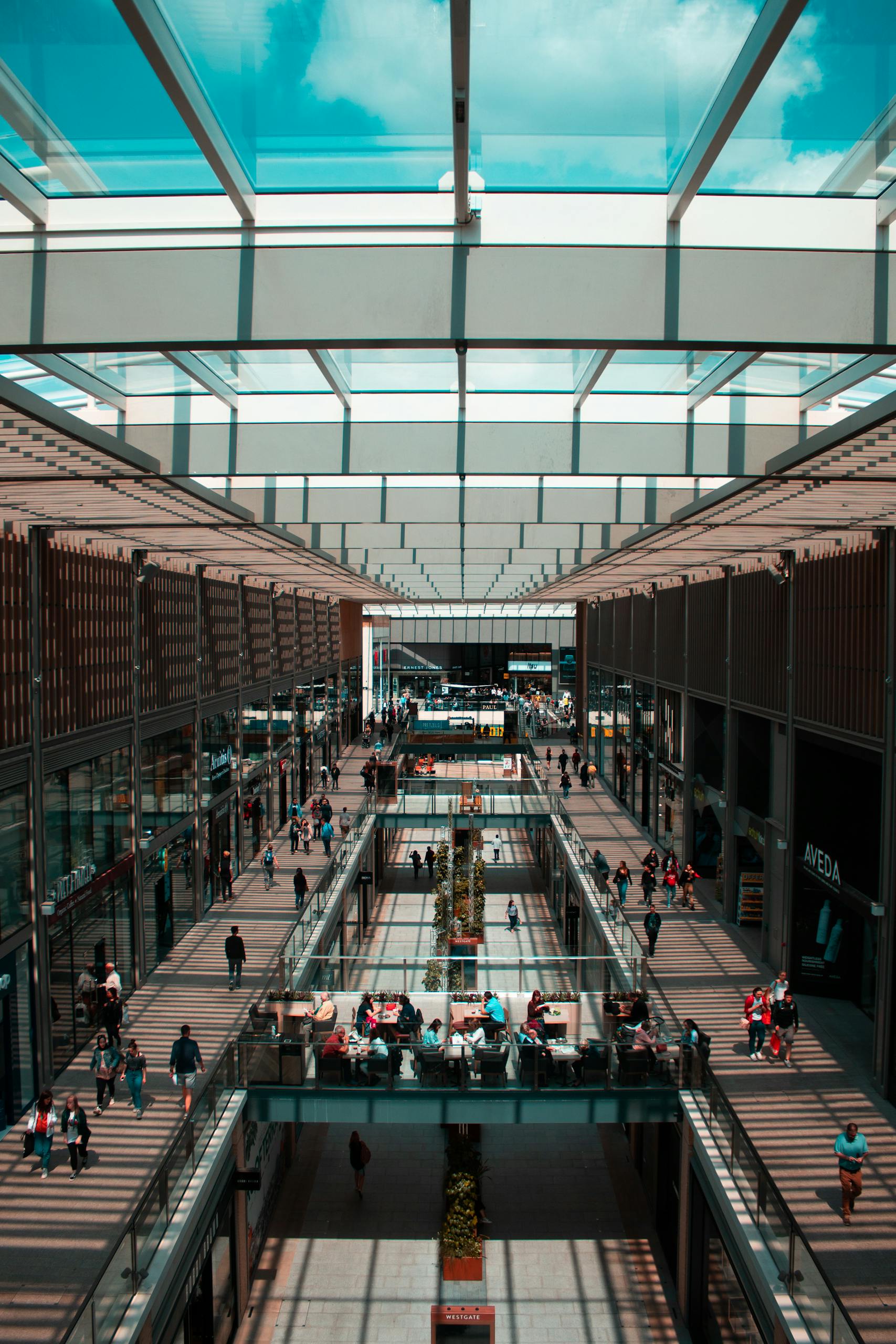 Explore the bustling atmosphere and sleek design of Germiston's modern shopping mall with natural light and glass panels.